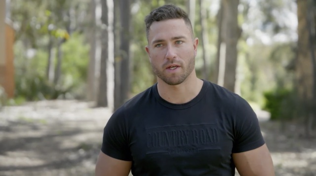 married at first sight's harrison boon standing in a park wearing a black country road t-shirt