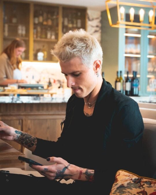 jed mcintosh the bachelors wearing black shirt looking at phone in restaurant 